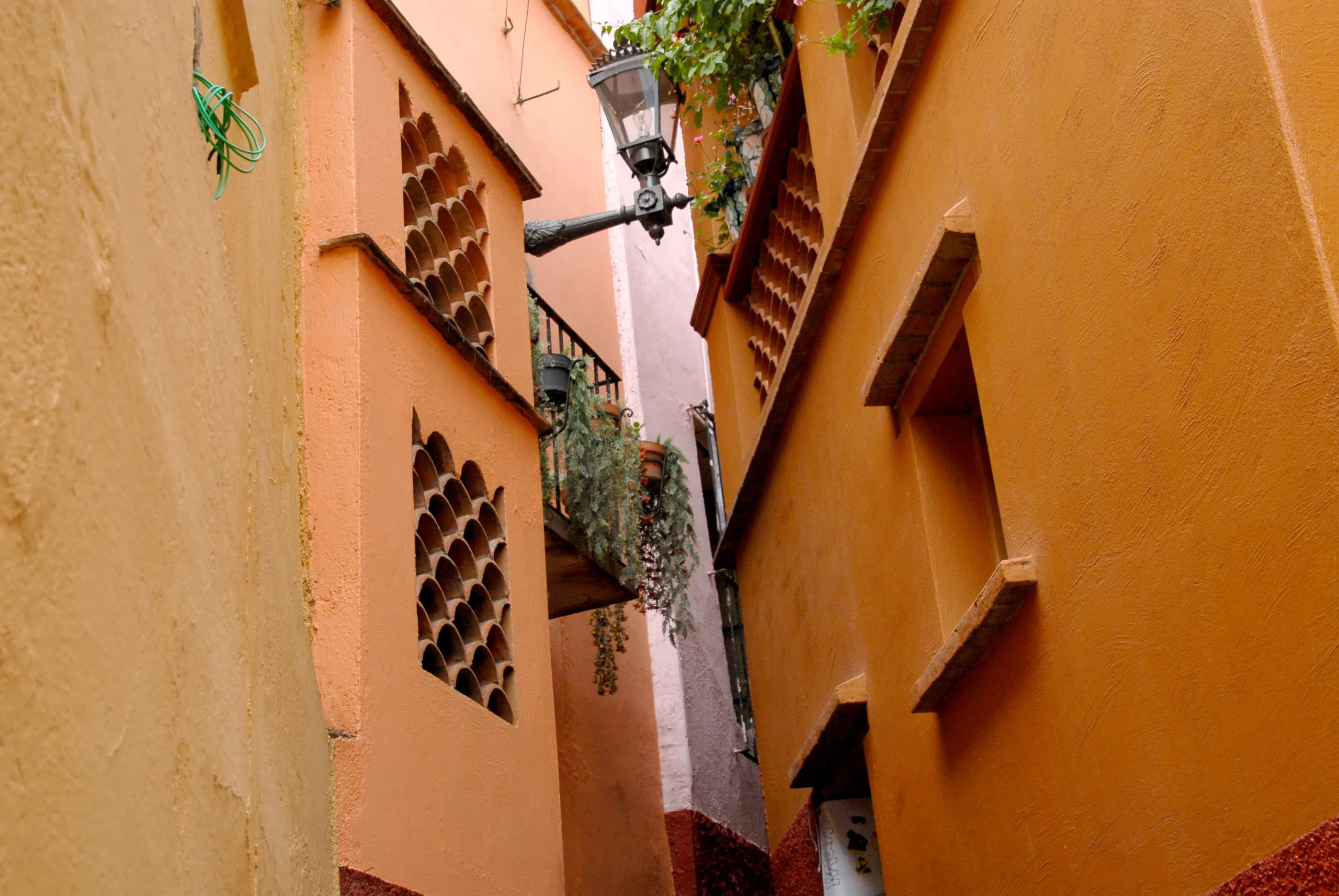Vista de baixo do Callejón del Beso em Guanajuato, com suas estreitas muralhas coloniais e varandas de casas de frente.